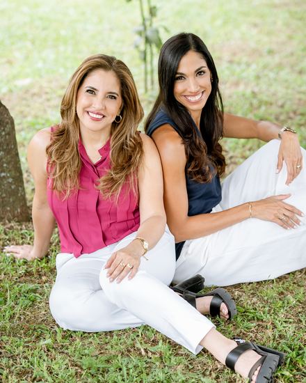 Josymar and Margarita Chacín sitting back to back on the grass in a garden.