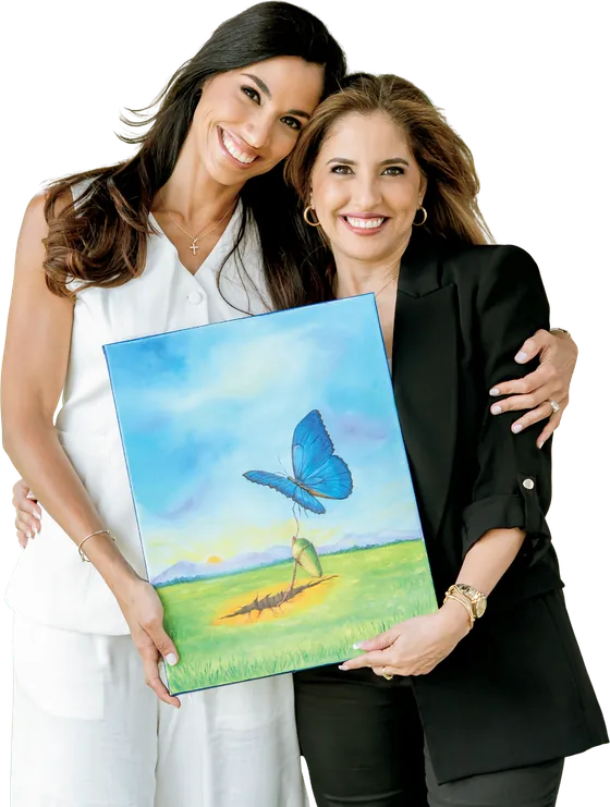 Margarita and Josymar Chacín embracing, holding the painting of a blue butterfly emerging from its cocoon.
