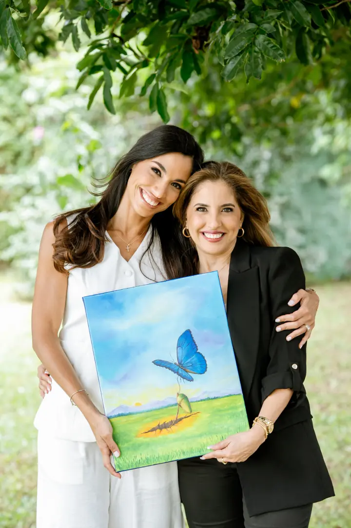 Page 310: Josymar and Margarita Chacín embracing, holding the painting of the blue butterfly.